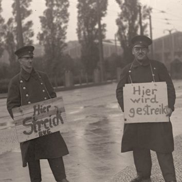 Streikende BVG Mitarbeiter halten Schilder in die Kamera. Schwarz-Weiß-Foto von 1932.